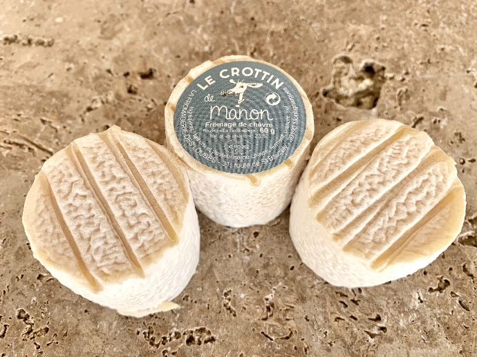 Trois Crottins de Manon, petits fromages de chèvre de 60 g de la Fromagerie des Loubes, posés sur la pierre